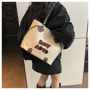 Detail view of beige tote bag with dark brown leather trim and DMT AUTO embroidery