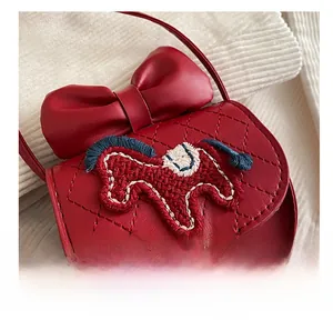Close-up of red crossbody bag with quilted diamond pattern and cute bow detail