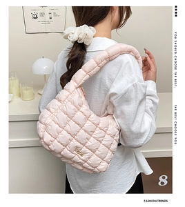 Detail of light pink puffy quilted handbag with gold metal logo and soft fabric texture