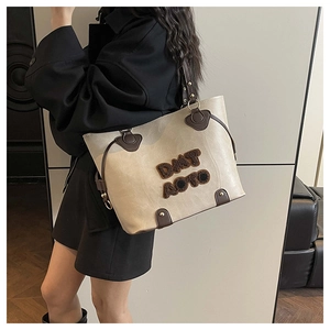 Detail of off-white PU leather tote bag with brown leather handles and plush letter embroidery