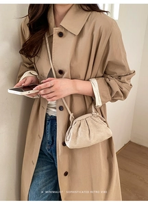 Detailopname van de beige geplooide cloud bag gecombineerd met een klassieke trenchcoat