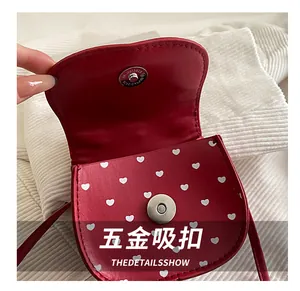 Detail view of the silver magnetic snap closure on the red heart-patterned leather bag