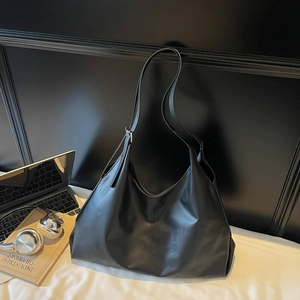 Detail view of large black leather hobo bag with laptop and office accessories
