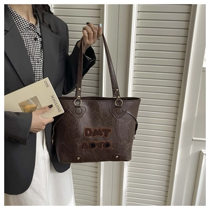 Detail of a brown marble-textured tote bag with plush letter embroidery and golden metal rings