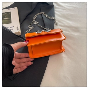 Détail du mini sac carré orange avec nœud en métal argenté et bandoulière chaîne