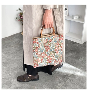 Detailed close-up of a floral jacquard canvas tote bag with a natural bamboo handle