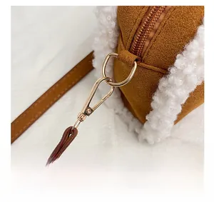 Détail de la quincaillerie dorée et de la bordure en peluche blanche sur un sac marron