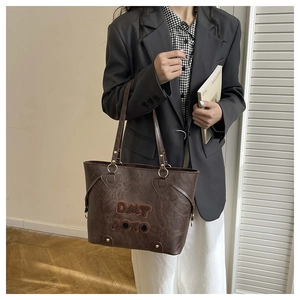 Detail of dark brown tote bag featuring vintage leather texture and gold hardware accents