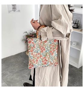 Detail view of floral tote bag featuring dark bamboo handles and vintage tapestry texture