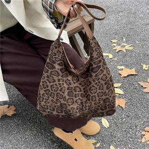 Close-up of leopard print hobo bag with brown strap on autumn ground scenery