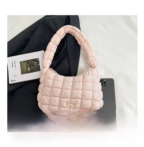 Macro shot of light pink quilted puffer bag showing nylon texture and golden logo