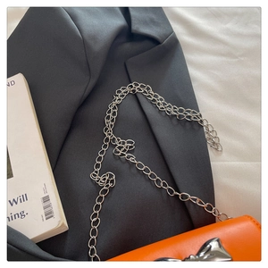 Détail d'un mini sac carré orange avec boucle nœud en métal argenté et chaîne
