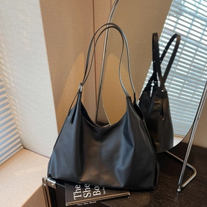 Detail view of a large black tote bag featuring glossy finish and elegant shoulder straps