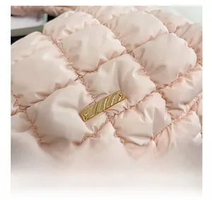 Close-up of pink quilted puffer bag with rectangle gold metal plaque detail