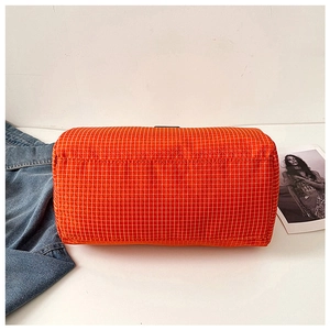 Detail view of durable nylon bottom stitching on orange checkered travel duffel bag