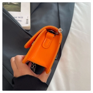 Vue latérale du mini sac carré orange vif avec chaîne argentée et détails de plis accordéon