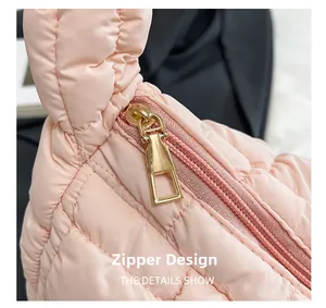 Close-up of golden metal zipper and quilted pink nylon fabric on a puffer bag