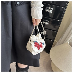 Detail of cream mini crossbody bag featuring a knit pony patch and ribbon decoration