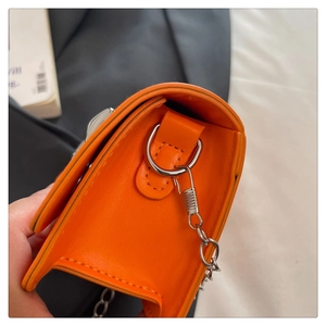 Détail de la mini sacoche orange avec chaîne argentée et coutures de précision