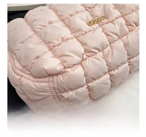 Detailed close-up showing the pink quilted puff bag fabric and its gold buckle detail