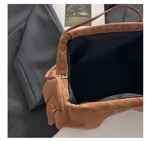 Detail view of the metal frame closure and black lining of the brown pleated bag