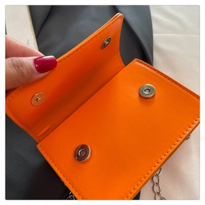 Vue détaillée du mini sac carré orange avec boucles magnétiques argentées et chaîne