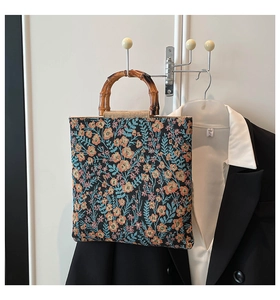 Detail of blue floral tote with bamboo handles against elegant blazer background