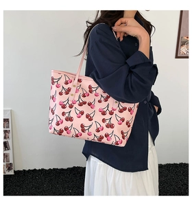 Detail view of pink cherry print tote bag on shoulder showing large capacity and smooth texture
