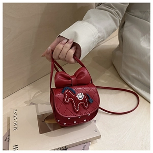 Detail of red crossbody bag featuring quilted PU leather and large decorative bow