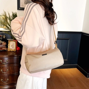 Beige quilted nylon cylinder sports crossbody bag worn by a model in a modern style