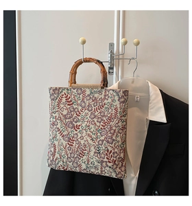 Detailed macro view of vintage floral tapestry fabric and natural bamboo handle on tote bag