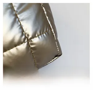 Macro shot of metallic champagne gold quilted fabric with detailed square stitching