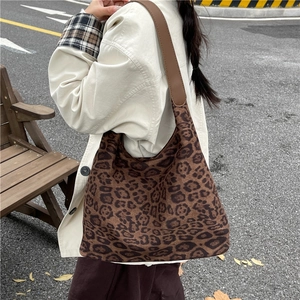 Retro leopard print tote bag with brown shoulder strap worn by a woman outdoors