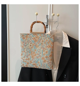 Detailed close-up of natural bamboo handle and floral fabric on a vintage tote bag