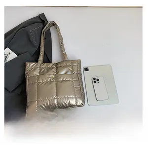 Detailed comparison of metallic gold quilted tote bag size with a tablet and phone