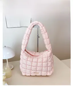 Detailed close-up of pink quilted puffer shoulder bag with elegant gold metal logo plate