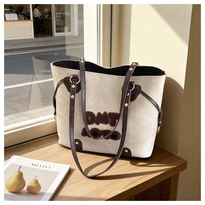 Detailed view of the beige textured leather tote with contrast brown trim and embroidery