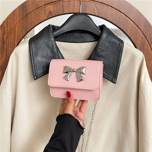 Gros plan d'un mini sac carré rose avec nœud en métal argenté et bandoulière chaîne