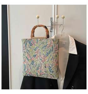 Detail of floral tapestry tote bag featuring natural bamboo handles and vintage print