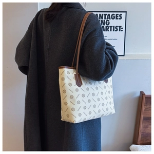Detailed view of monogram print tote bag worn with a black wool coat for daily commute