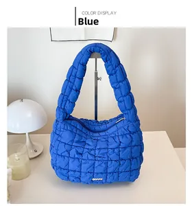 Detailed view of the blue quilted puff bag featuring soft texture and metal logo