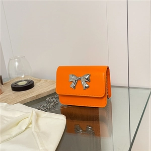 Détail du mini sac carré orange vif avec nœud métallique argenté et bandoulière