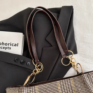 Details der karierten Stofftasche mit braunem Lederriemen und goldenen Metallringen