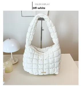 Detail view of off-white quilted puffer bag with chic golden metallic buckle ornament