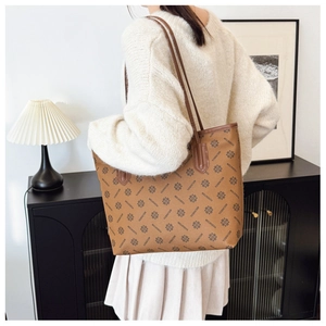 Detailed view of brown monogram tote bag with leather straps on model in warm interior