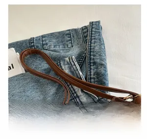 Detail view of brown suede handbag featuring high-quality metal zippers and leather handles