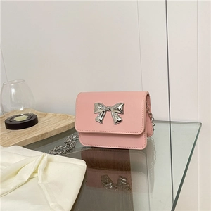 Détail du mini sac carré rose avec nœud métallique argenté et bandoulière en chaîne