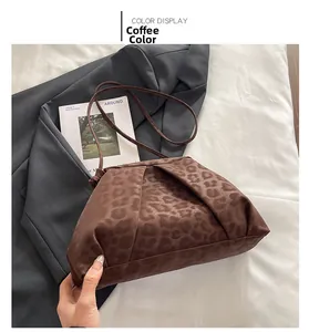 Detail view of leopard print ruched shoulder bag next to a fashion magazine on fabric