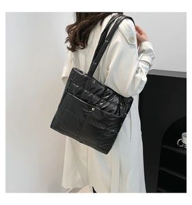 Detailed view of black quilted tote bag with glossy finish and magnetic closure texture
