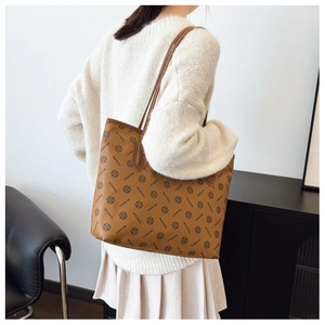 Detail of vintage brown tote bag with logo print and leather straps on model shoulder